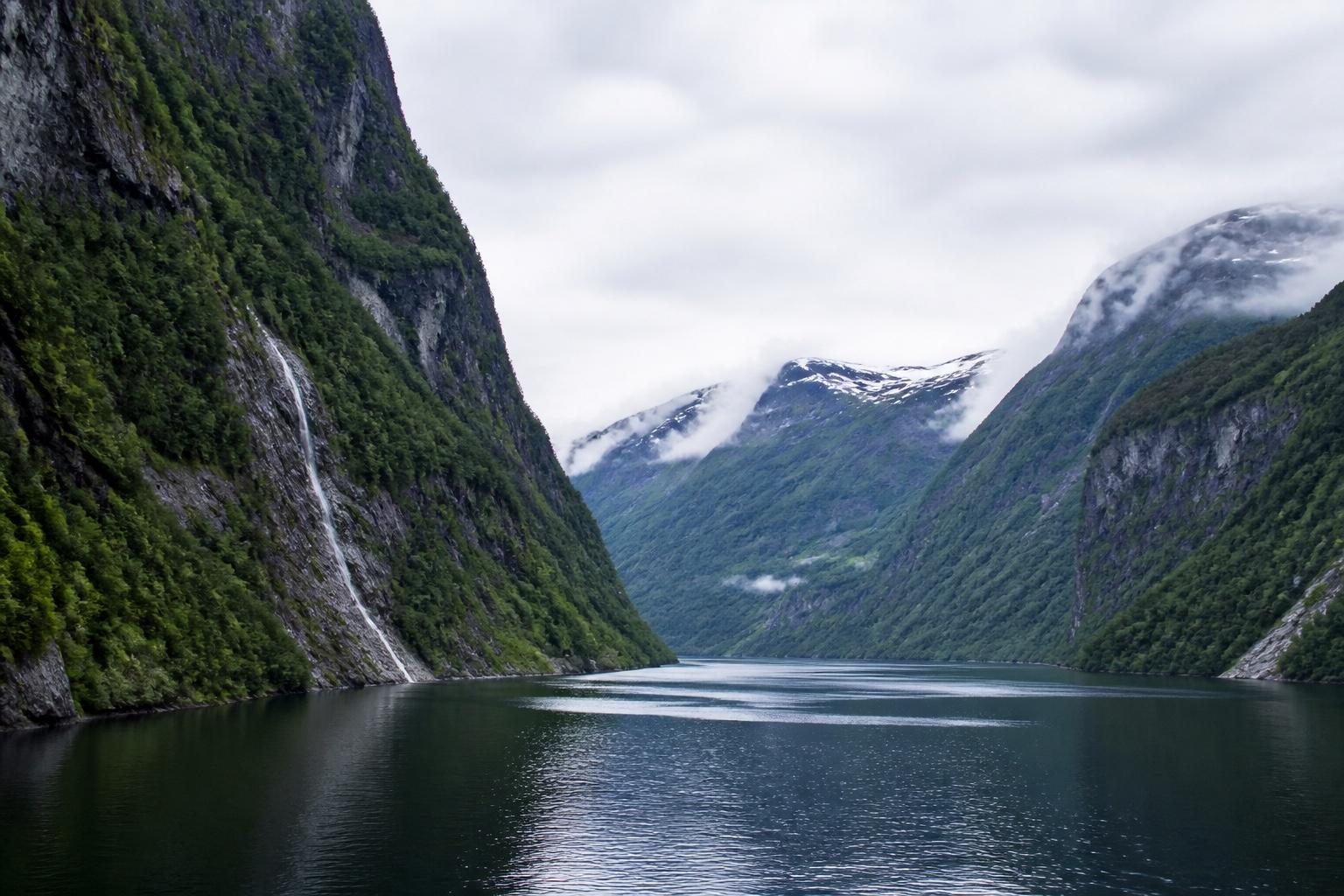 Steile grüne Fjordwände und Wasserfälle an einem norwegischen Fjord